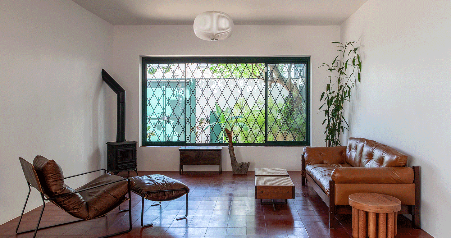 Casa em São Paulo, serralheria verde, paisagismo, reforma, jardim, piso ladrilho vermelho, sala de estar, poltronas, sofá de couro, lareira.
