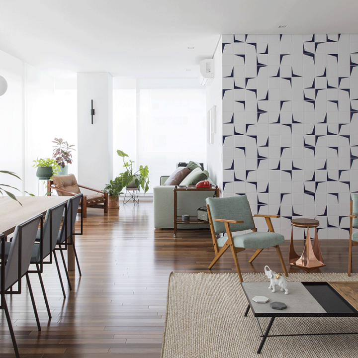 Sala ampla do Apartamento Vértice, com piso de madeira, parede de azulejos geométricos e poltrona verde, na Vila Olímpia