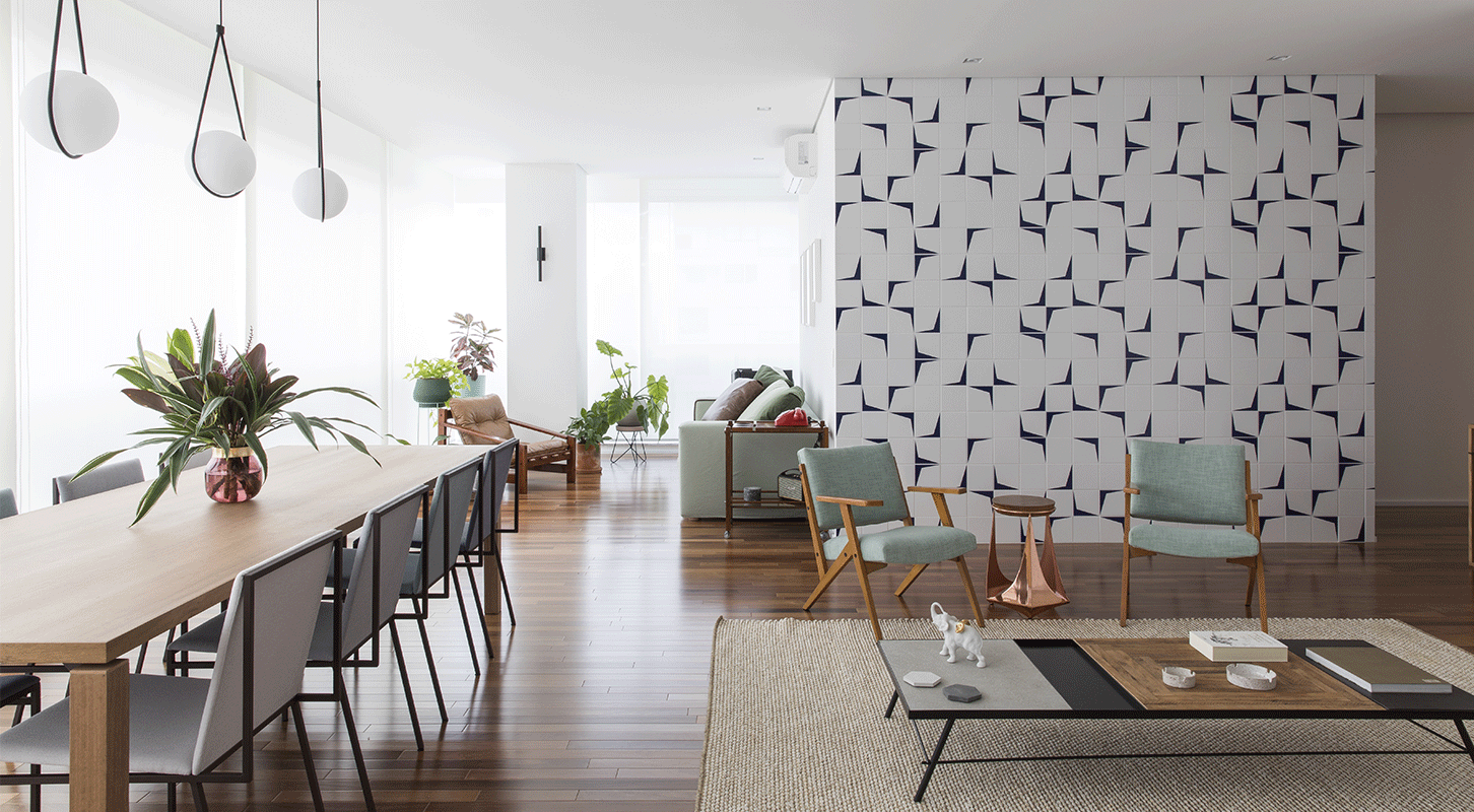 Sala ampla do Apartamento Vértice, com piso de madeira, parede de azulejos geométricos e poltrona verde, na Vila Olímpia