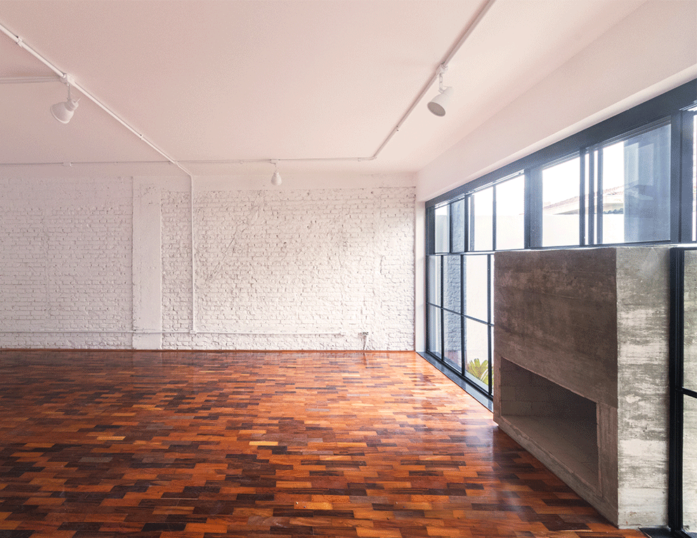 Sala da Casa Lareira com piso de taco, parede de tijolo branco e lareira de concreto junto aos caixilhos