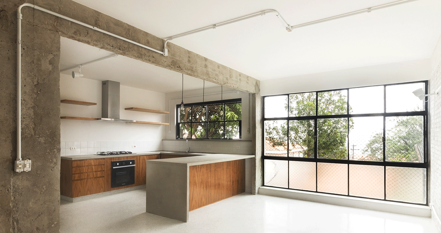Cozinha da Casa Lareira com bancada de madeira e concreto, prateleiras e janela de caixilho preto